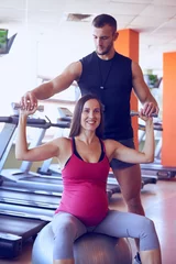  Smiling pregnant woman exercising in gym with personal trainer © ArtFamily