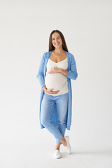 Joyful pregnant woman with hands on belly posing at camera