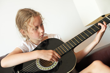 Obraz premium Little girl learns to play guitar.