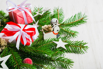 New Year and Christmas background on an white wooden background. View from above. Christmas tree branches and snow, gifts and decorations.