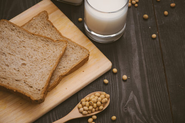 Breakfast with soy beans in spoon, soy milk and sandwich on wooden background