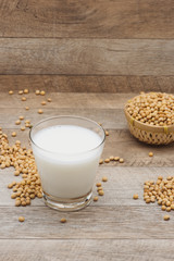 Glass with soy milk and soy bean on wooden background