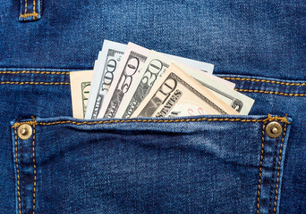 Dollar bills on back blue jeans pocket.