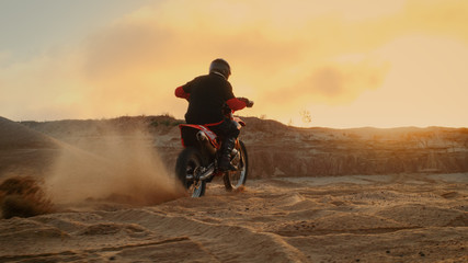 Fototapeta premium Professional Bike Rider Blasts-off on His FMX Motorcycle Over Sandy Off-Road Track. Scenic Sunset is on the Background.