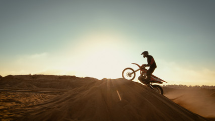 Professional Motocross Motorcycle Rider Jumping Over the Dune and Further Down the Off-Road Track....