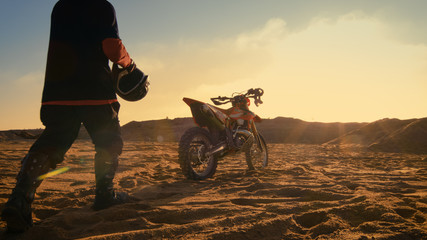 Low Angle Shot of the Professional Motocross Driver Getting Ready to Ride His FMX Dirt Bike on the...