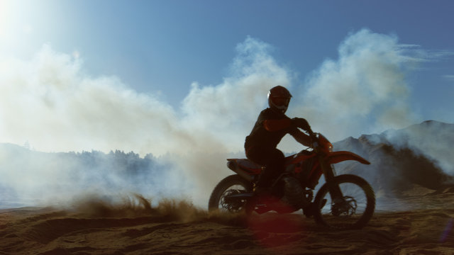 Professional Motocross FMX Motorcycle Rider Drives Through Smoke and Mist Over the Dirt Road Track.