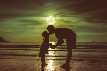 Father's day. Silhouette side view of loving child kissing her father.