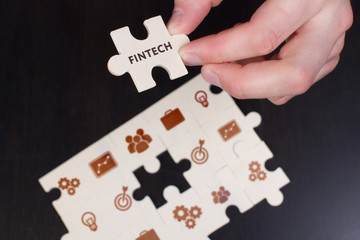 The concept of business, technology, the Internet and the network. A young businessman collects a puzzle with the proper inscription: Fintech