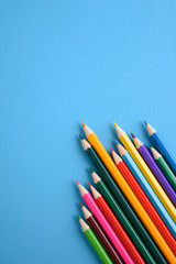  Colored crayons background. Many different colored pencils on blue background