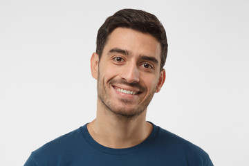 Close up shot of smiling attractive man in blue t-shirt isolated on gray background