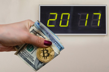 Golden bitcoin coin on women's hand on blurred us dollar bills background copy space 2017,  year,...