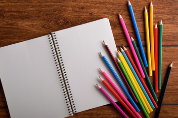 blank paper and colorful pencils on old wooden table