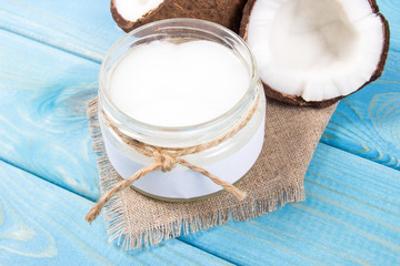 Coconut oil and fresh coconuts on a wooden table.