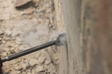 Worker with electrical hammer cleaning red brick wall outdoor