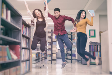 Fototapeta premium Group of student jumping with hand up in University library