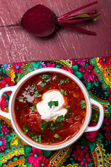 Ukrainian traditional borsch. Russian vegetarian red soup  in white bowl on red wooden background. Top view.  Borscht, borshch with beet.