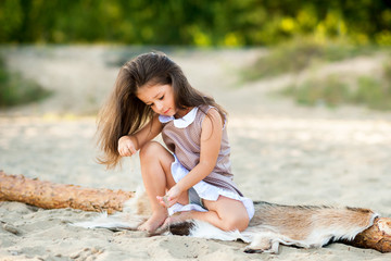 beautiful little girl on the beach playing with sand and having fun.