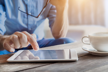 Businessman using digital tablet computer on wooden table, coffee, screen
