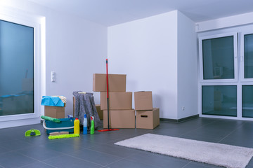 Helle, leere Luxuswohnung mit Kartons und Reinigungsmitteln im linken Teilbereich