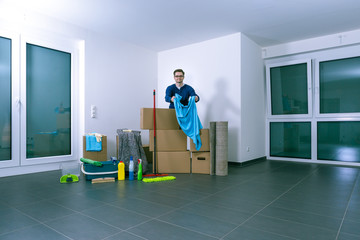 Mann reinigt eine große, helle, leere Luxuswohnung. Er faltet ein großes Putztuch zusammen.