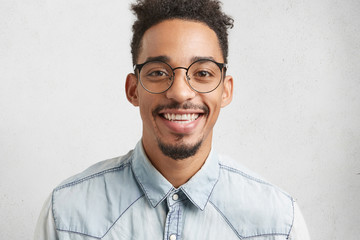 People, positiveness and happiness concept. Glad smiling male teenager wears big spectacles, being happy to have date with beautiful girl, prepares thoroughly, isolated over white background