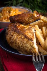 Roasted chicken with french fries on a plate.