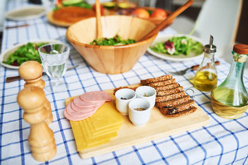 High angle  of delicious wholesome food on rustic table over gingham blue tablecloth: sandwiches and  green salad in wooden bowl