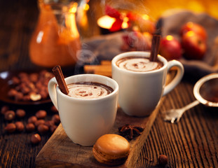 Warme chocolademelk met room, bestrooid met aromatische cacao in witte kopjes, op een rustieke houten tafel