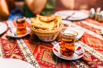 Close-Up of delicious Red Turkish tea with traditional pear shaped glass on ethno patterned tablecloth in cafe