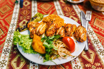Flat view of the plate in the restaurant with Fried chicken wings with bulgur and vegetables. Traditional Turkish cuisine