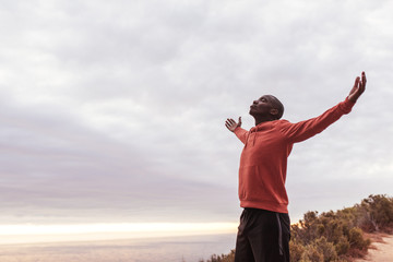 Young African man standing on a trail outside embracing nature 