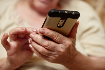 Hands of an elderly woman holding a mobile phone close-up