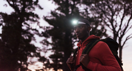 Young African man wearing a headlamp jogging at dusk