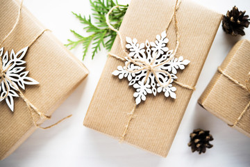 Christmas handmade gift boxes decorated with craft paper and white snowflakes on white wooden background top view. Merry christmas greeting card. Winter xmas holiday theme. Happy New Year.