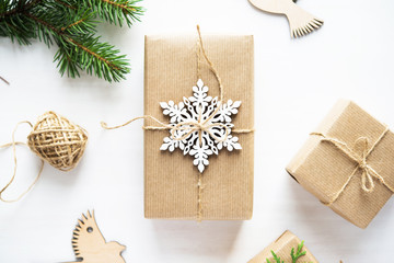 Christmas handmade gift box decorated with craft paper and white snowflakes on white wooden background top view. Merry christmas greeting card. Winter xmas holiday theme. Happy New Year. Flat lay.