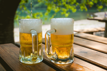 Pair of freshly filled beer glasses, over a table