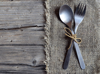 Cutlery set:fork and spoon on burlap cloth on rustic wooden table.Cutlery on old wooden...