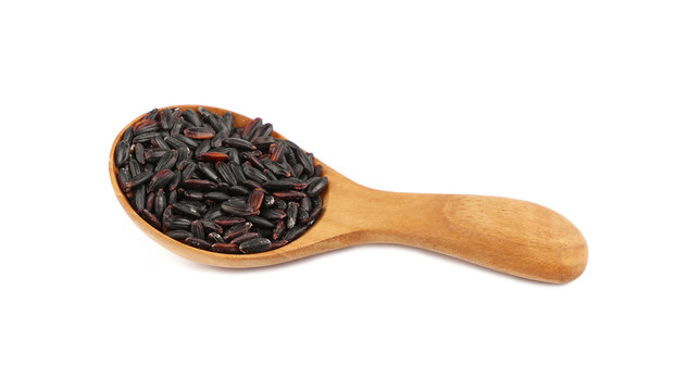 Black purple raw rice in wooden scoop on white