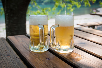 Pair of freshly filled beer glasses, over a table
