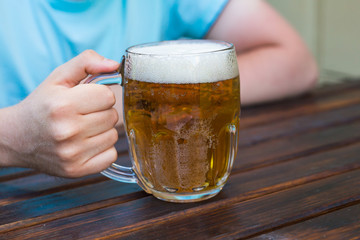 Hand holding a glass of beer on wooden table