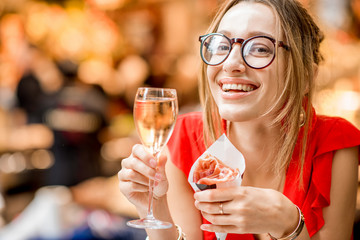Young woman in red dress eating jamon traditional spanish dry-cured ham with glass of wine sitting at the Barcelona food market