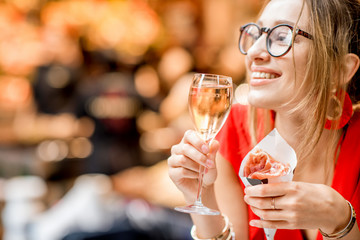 Young woman in red dress eating jamon traditional spanish dry-cured ham with glass of wine sitting at the Barcelona food market