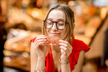 Young woman in red dress eating jamon traditional spanish dry-cured ham sitting at the Barcelona...