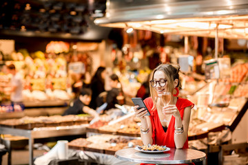 Young woman in red dress having lunch with mussels and rose wine sitting at the food market