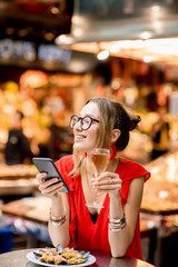 Young woman in red dress having lunch with mussels and rose wine sitting at the food market