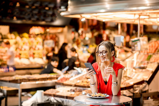 Fototapeta Young woman in red dress having lunch with mussels and rose wine sitting at the food market