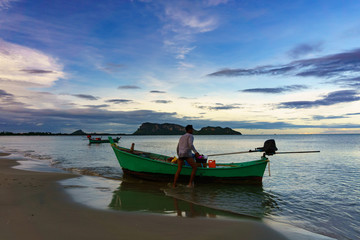 beautiful panorama landscape of silhouette fisherman and boat floating in sea at the beach at dusk in the evening . boat in the sea in evening when sunset with golden light with mountain background.