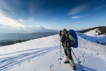 Hiker is posing to the camera in winter mountains