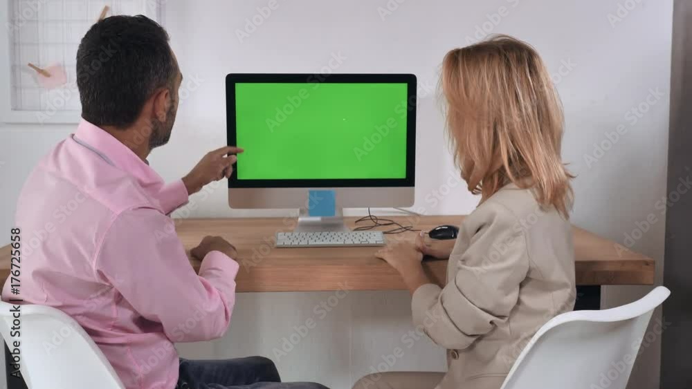 Poster People in the office. Man showing presentation using green screen on computer. Mixed race manager telling about new products caucasian businesswoman listening and looking on display